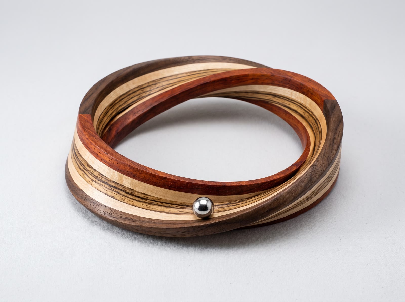 Un anillo de madera tallado en un bucle continuo, con una esfera de acero engastada.