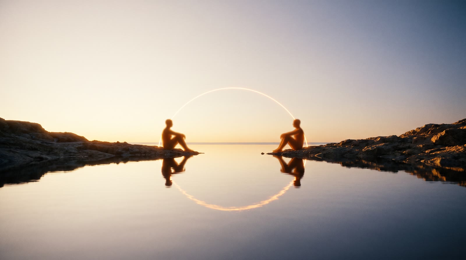 Dos siluetas cálidas sentadas en orillas opuestas de una bahía en calma, unidas por un arco de luz dorada entre sus frentes, reflejado en el agua.